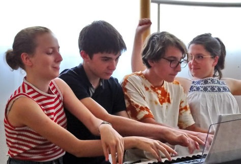 Quatre pianistes jouant sur un piano